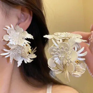 Detailed view of white leather flower C-shaped earrings with delicate pearl accents.