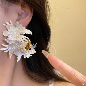 Detailed macro shot of elegant white leather floral C-shaped earrings worn by a model