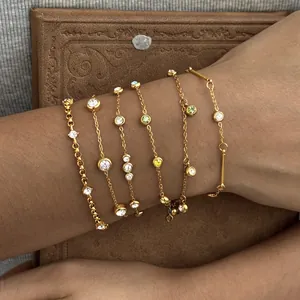 Detailweergave van zes goudkleurige roestvrijstalen armbanden met gekleurde zirkoonstenen