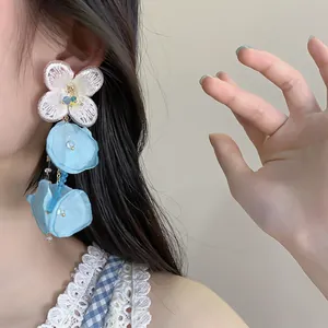 Detail shot of elegant blue chiffon flower tassel earrings worn for a summer look