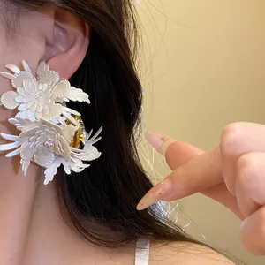 Close-up of elegant cream leather flower C-shape stud earrings on ear