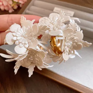 Macro view of white leather flower earrings with pearls and gold C-shaped base