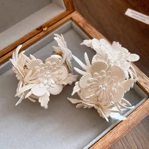 Detailed close-up of handmade cream leather flower C-shaped earrings with pearls