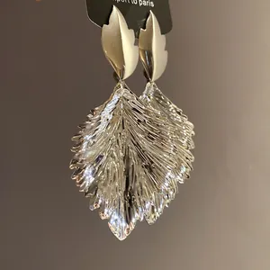 Close-up macro detail of silver metallic pleated leaf dangle earrings with intricate texture.