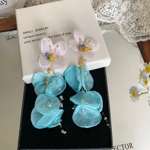 Close-up of elegant pink embroidered flower and blue chiffon petal tassel earrings