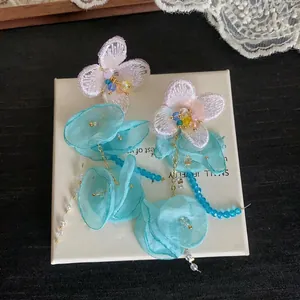 Detail view of elegant fairy-style chiffon flower tassel earrings with blue crystal beads