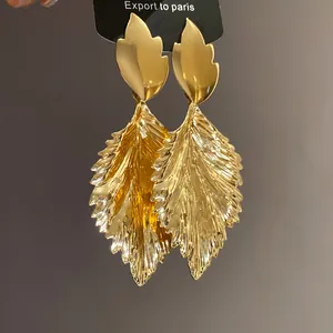 Detailed view of golden pleated leaf drop earrings with intricate metallic texture