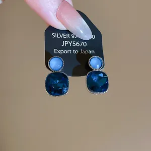 Close-up of elegant blue square rhinestone earrings with silver 925 backing card.