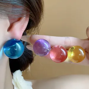 Primo piano di orecchini a sfera in resina colorata in vivaci tonalità ispirate alla dopamina