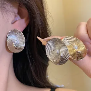 Elegant 18k gold plated oval earrings featuring radiant texture and central pearl accents.
