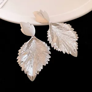 Detailed macro view of stylish silver pleated leaf drop earrings with metal texture