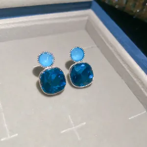 Macro view of elegant blue square earrings with sparkling faceted stones and silver trim