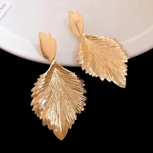 Detailed view of large golden textured leaf-shaped earrings with crinkled metal finish.