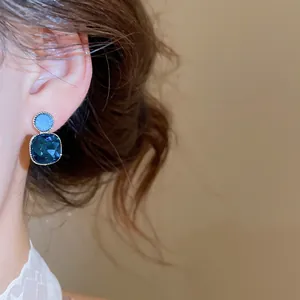 Detailed close-up showing the sparkling facets of blue crystal square stud earrings on ear