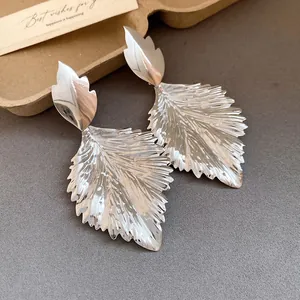 Macro detail of silver leaf earrings featuring unique wrinkled metallic leaf texture.