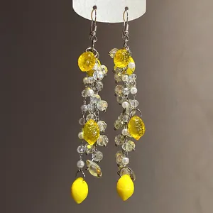 Close-up of yellow resin lemon drop earrings with elegant pearl and beaded details