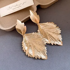 Detailed close-up showing the metallic folded leaf texture of these gold dangle earrings