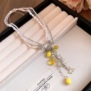 Close-up of pearl and resin lemon pendant necklace on a jewelry display tray.