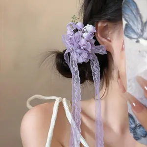 Side detail view of a purple chiffon lily of the valley hair clip with elegant lace ribbons.