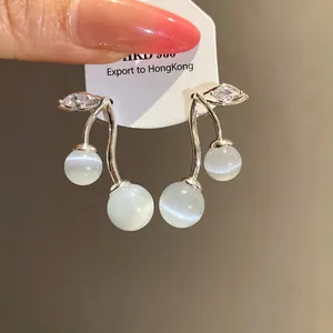 Close-up detail of exquisite silver cherry earrings featuring cat's eye stones and zircons
