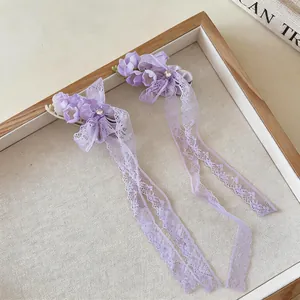 Detail view of purple chiffon flower hair clips with elegant lace tassels and rhinestones.
