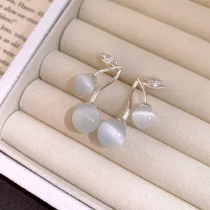 Close-up of cat's eye stone cherry earrings with zircon details on silver studs