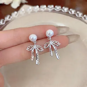 Elegant French style silver bow earrings with pearl and crystal detail on a decorative plate