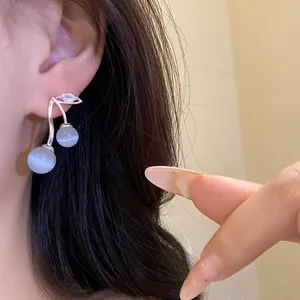 Close-up of elegant silver cat-eye stone cherry drop earrings with zircon leaf detail.
