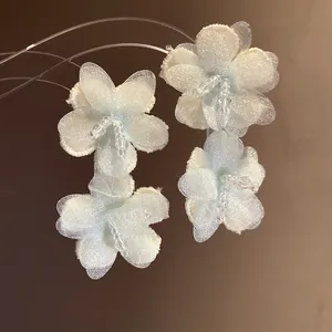 Close-up of light blue fabric flower earrings with delicate organza petals and beads