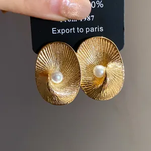 Detail of 18k gold plated oval earrings featuring textured surface and center pearl