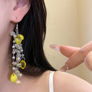 Close-up detail shot of yellow resin lemon and pearl beaded dangling earrings for women