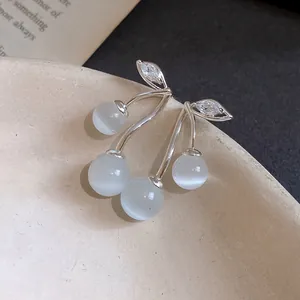 Detailed view of elegant silver cherry earrings with zircon leaves and cat eye stones.