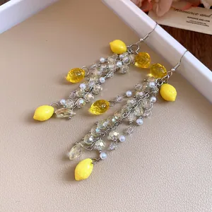 Close-up of vibrant resin lemon earrings featuring pearl accents and clear faceted beads