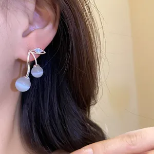 Close-up of cherry-shaped earrings with cat's eye stones and zircon crystals