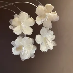 Macro detail of elegant white mesh flower earrings with delicate beaded centers