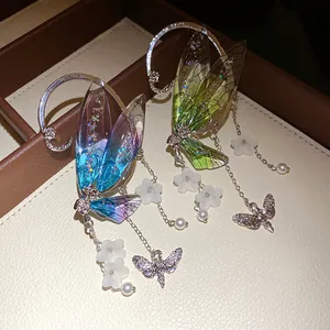 Close-up of fairy wing earrings with resin wings, white flowers and butterfly pendants