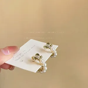 Close-up of French flower pearl earrings with green enamel detail on display card.