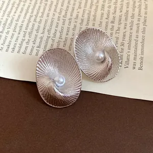 Macro detail showing the radial texture and pearl of these oval silver needle stud earrings