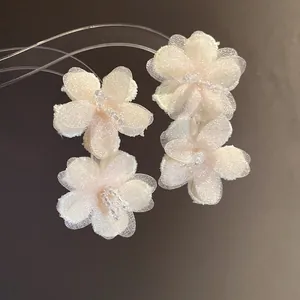Close-up detail of elegant white mesh flower earrings with beaded centers