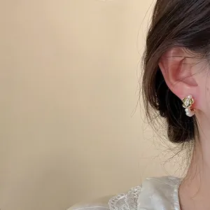 Detail shot of elegant floral pearl stud earring worn on ear, French minimalist style.
