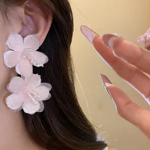 Close-up of pink fabric flower earrings on ear for a sweet beach vacation aesthetic