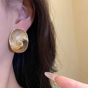 Close-up of elegant 18k gold plated oval textured stud earring with center pearl