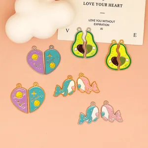 Macro view of cartoon avocado, heart, and whale enamel charms for DIY jewelry.