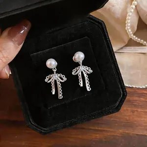 Close-up detail of elegant French style bow and pearl drop earrings in black jewelry box