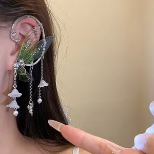 Macro view of forest style resin wing earrings with delicate flower and pearl drops