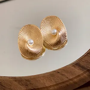 Macro view of gold plated earring surface showing fine spiral ridges and a polished pearl
