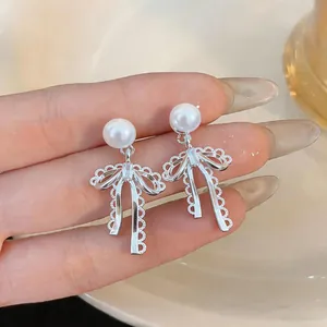 Close-up detail of elegant silver-toned bow knot earrings featuring lustrous white pearls