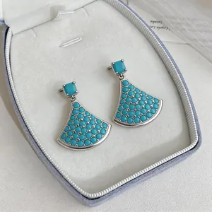 Exquisite detailed close-up of turquoise fan-shaped earrings presented in a white jewelry box.