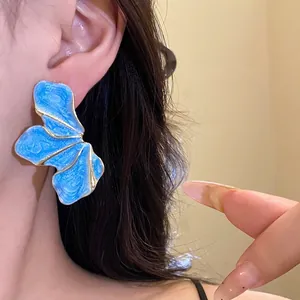 Vintage blue enamel flower petal earrings with gold trim worn by an elegant model