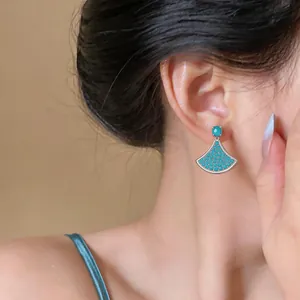 Detail view of elegant blue fan-shaped zircon stud earrings worn on ear for women.